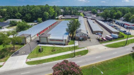 Exterior view of a self-storage facility with modern architecture and clean landscaping, under a partly cloudy sky.