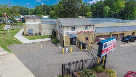 Exterior of a self-storage facility with multiple units, a clean driveway, and well-maintained grounds, set against a clear sky.