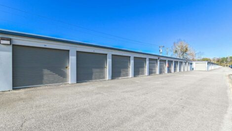 Exterior view of a self-storage facility with a modern design, featuring a clean, open parking area and clear signage under a bright, clear sky.