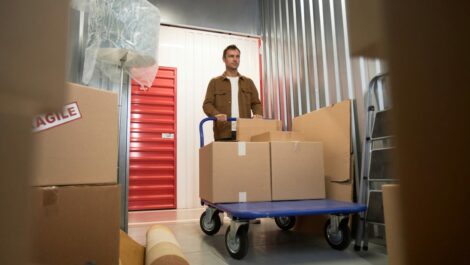 A man pushing a cart of sealed boxes into a storage unit.