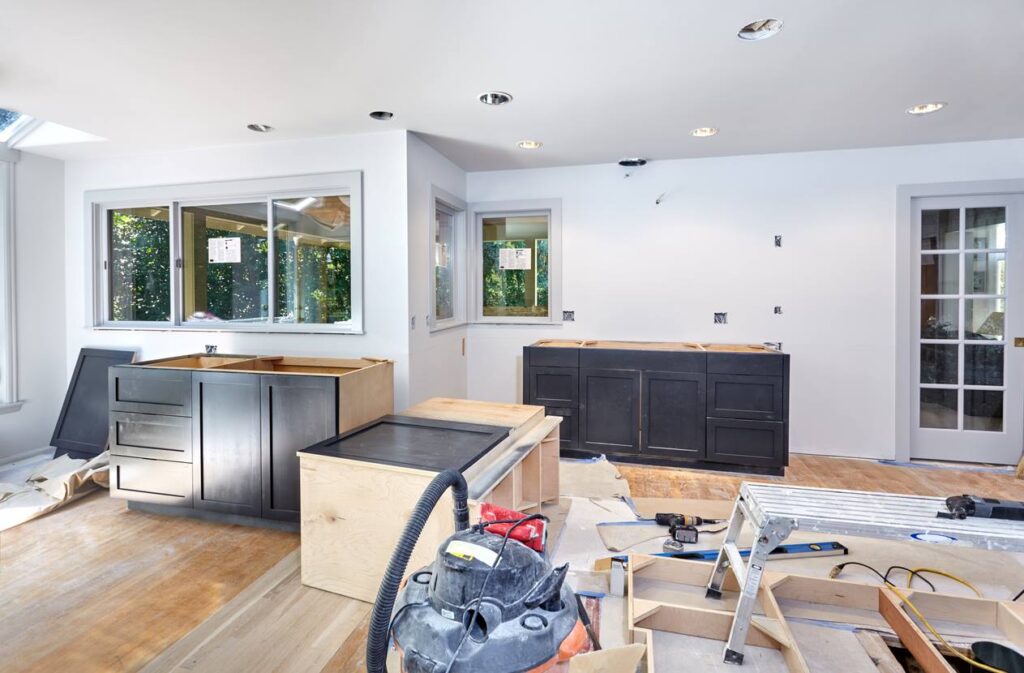 A kitchen in the middle of renovations with disassembled cabinets scattered around.