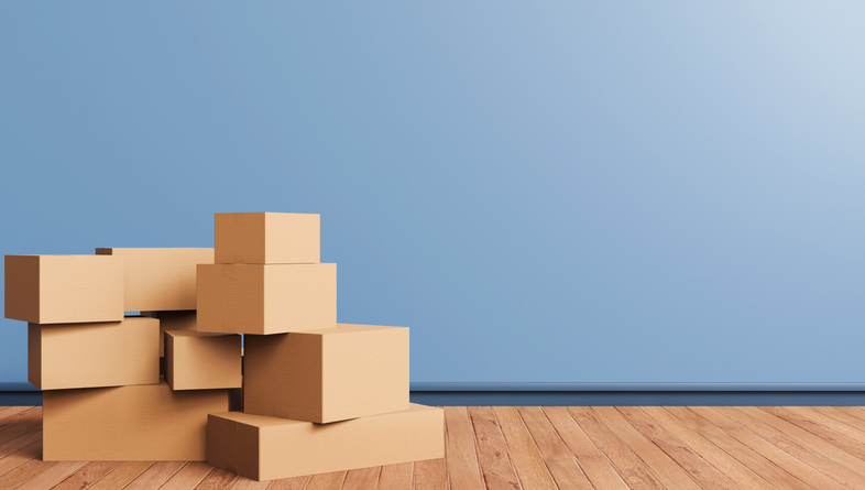 Cardboard boxes in small stacks on a wooden floor in front of a blue wall.