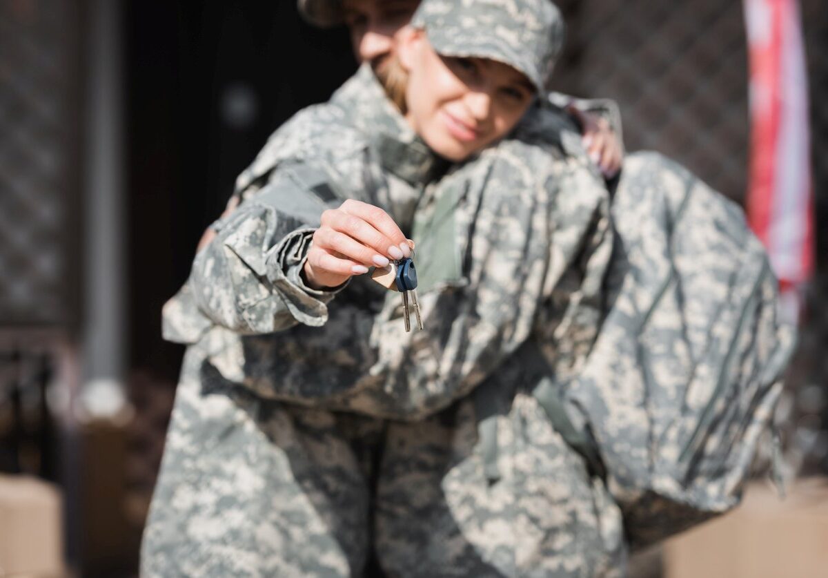 A military couple hugs while showing the camera their homes news keys.